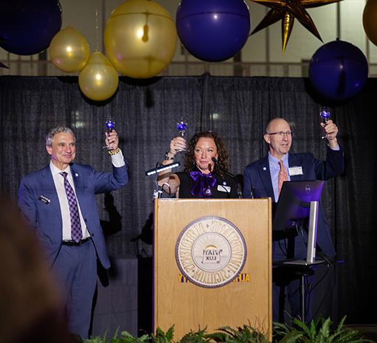 three people (two men, a woman) raising glasses for a toast