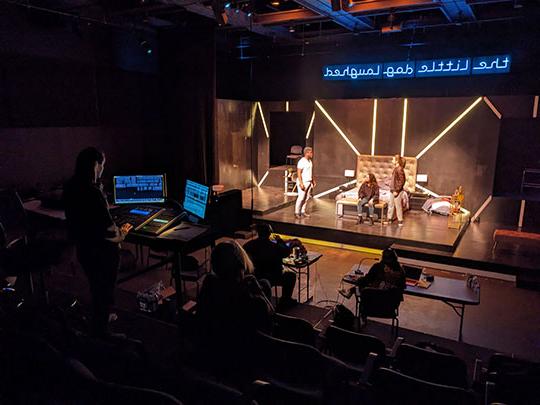 people at computers monitoring a stage production