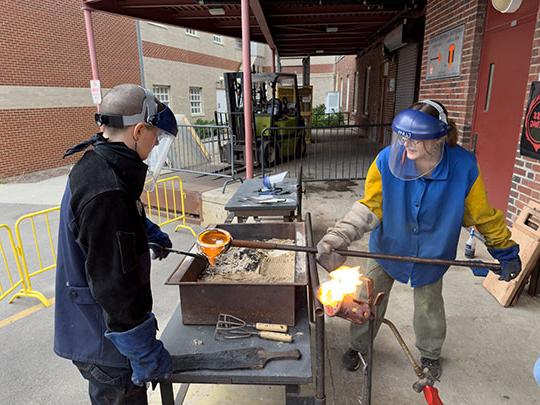 photo of two people pouring molten glass into a mold