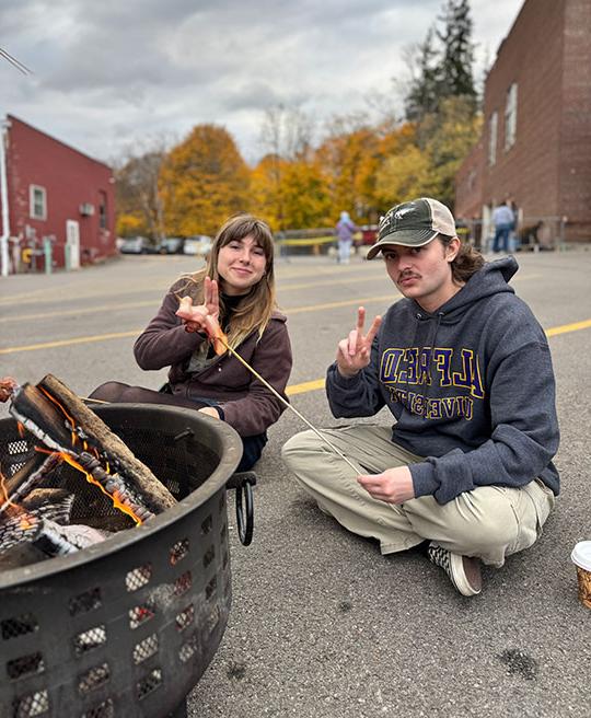 two people sitting by a fire eating a snack