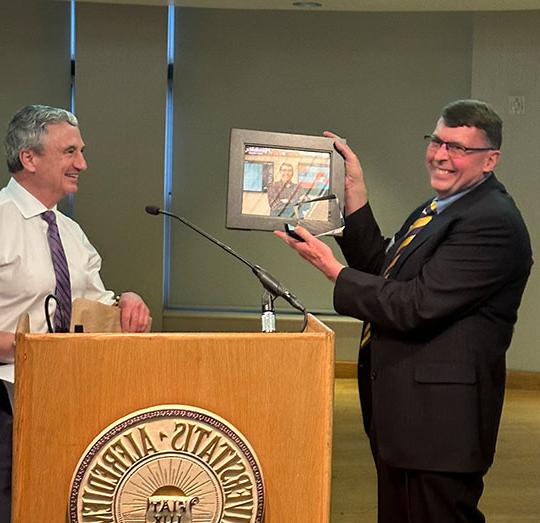 two men standing by a podium, one holding a plaque