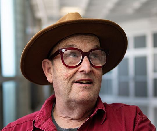 headshot of man with hat and glasses